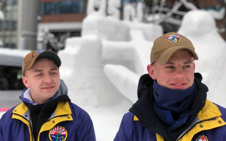 Builder 3rd Class Kyle Antrobus and Information Systems Technician 3rd Class Sean Ingraham greet visitors at the Navy team's sculpture Thursday, Feb. 7, at the 2019 Sapporo Snow Festival.