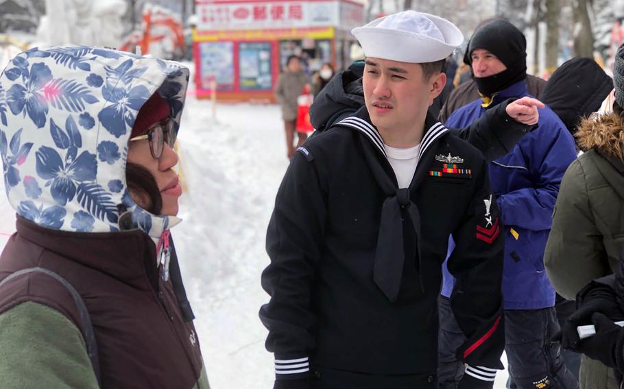 Yeoman 2nd Class Zachary Sakuda interacts with Sapporo Snow Festival attendee Yoshiko Aoki as she admires the Navy's 2019 snow sculpture on Thursday, Feb. 7.
