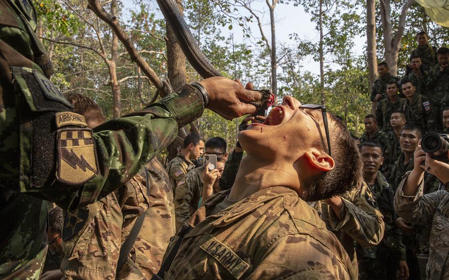 Royal Thai Armed Forces Master Sgt. 1st Class Saengchai Seeuthai pours cobra blood into the mouth of a U.S. soldier of the 20th Infantry Regiment during exercise Cobra Gold 19 at Phitsanulok, Thailand, on Feb. 13, 2019.