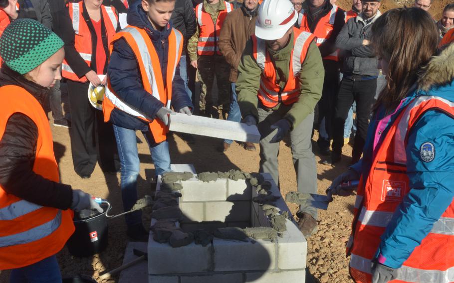 With the help of the construction workers, students from the current Wiesbaden Elementary School bury a time capsule in the foundation of the new school in Wiesbaden, Germany, on Thursday, Feb. 14, 2019.