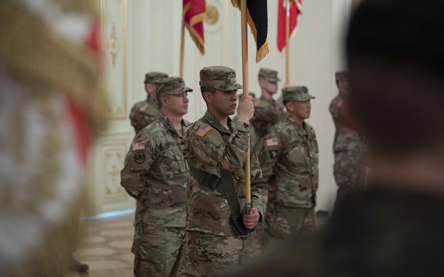 Guidon bearers and leadership for the 1st Armored Brigade Combat Team, 1st Infantry Division, listen during the transfer of authority ceremony in Zagan, Poland, Feb. 12, 2019.
