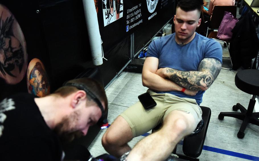 Spc. Alexander Schirmers, a medic with the Army's 2nd Cavalry Regiment, waits for his tattoo to finish at the Grafenwoehr Tattoo Expo, in Grafenwoehr, Germany, Sunday, April 8, 2019.