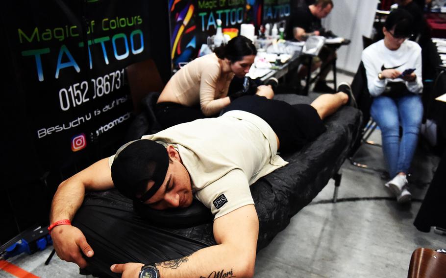 Spc. Emilio Lopez, an infantryman with the Army's 2nd Cavalry Regiment, gets a band logo tattooed on his calf at the Grafenwoehr Tattoo Expo, in Grafenwoehr, Germany, Sunday, April 8, 2019.