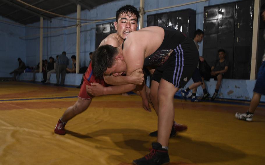 Two young wrestlers, Salman, 24, in red, and Najibullah, 19, in blue, grapple during a night session at the Maiwand Wrestling Club in Kabul on April 7, 2019.