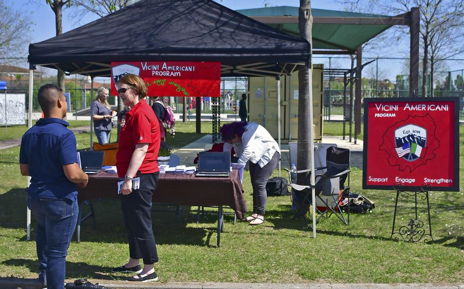 Master Sgt. Corina Cruceanu, one of the Vicini Americani program managers, speaks with a potential volunteer during the Spring Into Spring Festival that was held at Aviano Air Base's Freedom Park, April 19, 2019.  The program is composed of both American and Italian community members who work together to encourage new American individuals and families to embrace their local community.