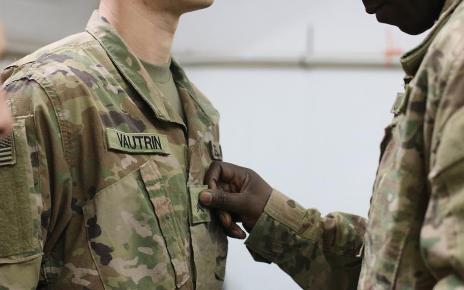 Sgt. 1st Class Colin Anderson attaches sergeant rank on Jon Vautrin's uniform during a promotion ceremony at Camp Arifjan, Kuwait, April 1, 2019. The Army is revamping its promotion board processes to focus promotions on merit, not time served. It is the first major overhaul of the system since 1969, the Army said.