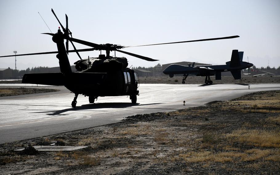 An Afghan air force UH-60 Black Hawk helicopter and an MQ-9 Reaper drone used during counterterrorism operations by the U.S. military in Afghanistan, cross paths at Kandahar Air Field on Nov. 5, 2017.