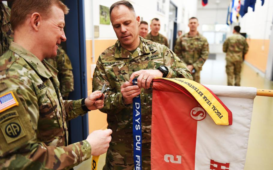 Col. Thomas Hough, the 2nd Cavalry Regiment commander, left, and Brig. Gen. Christopher LaNeve, the 7th Army Training Command commanding general, fix "No DUI Streamers" to a squadron's guidon during a ceremony, Friday, April 19, 2019.