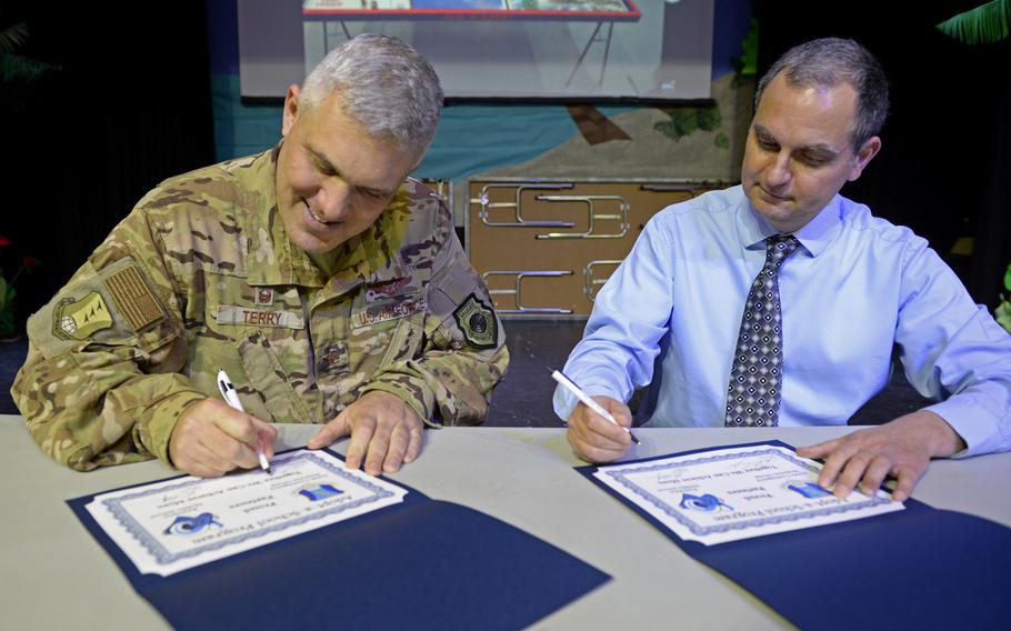 Col. Jason Terry, 435th Contingency Response Group commander, and Ramstein Middle School Principal Dan Petritz sign partnership statements during the robotics and music exhibition at Ramstein Middle School, Germany, May 9, 2019.
