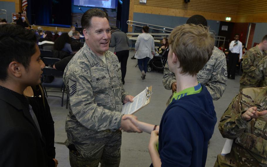 Master Sgt. Daniel Williams, 435th Contingency Response Group, congratulates Carbin Markus on his research project during the robotics and music exhibition at Ramstein Middle School, Germany, May 9, 2019.