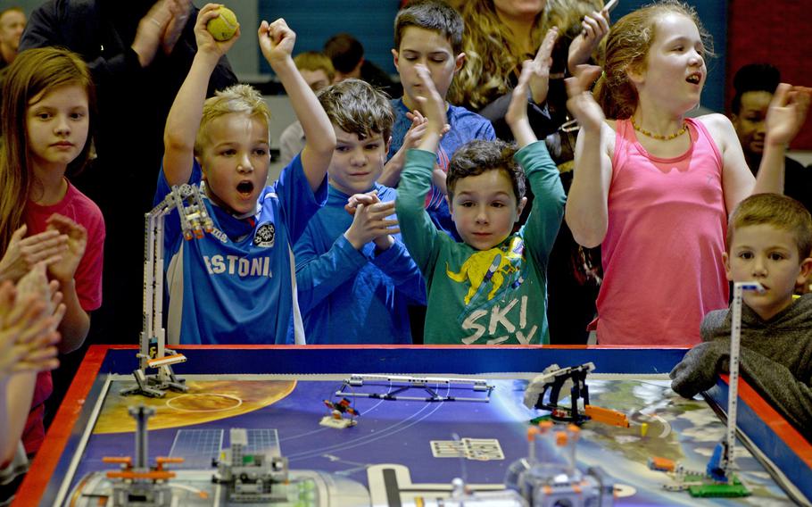 Young kids cheer as an autonomous robot completes a mission during the table demonstration at the robotics and music exhibition at Ramstein Middle School, Germany, May 9, 2019.