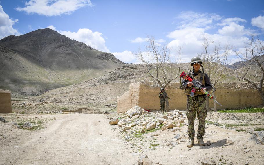 Afghan soldiers guard a temporary checkpoint in Logar province on May 2, 2019.  Taliban fighters often descend from these mountains (background) while moving around the province.