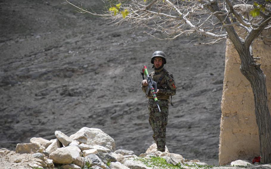 An Afghan soldier guards a temporary checkpoint in Logar province on May 2, 2019.  Taliban fighters often descend from these mountains (background) while moving around the province.