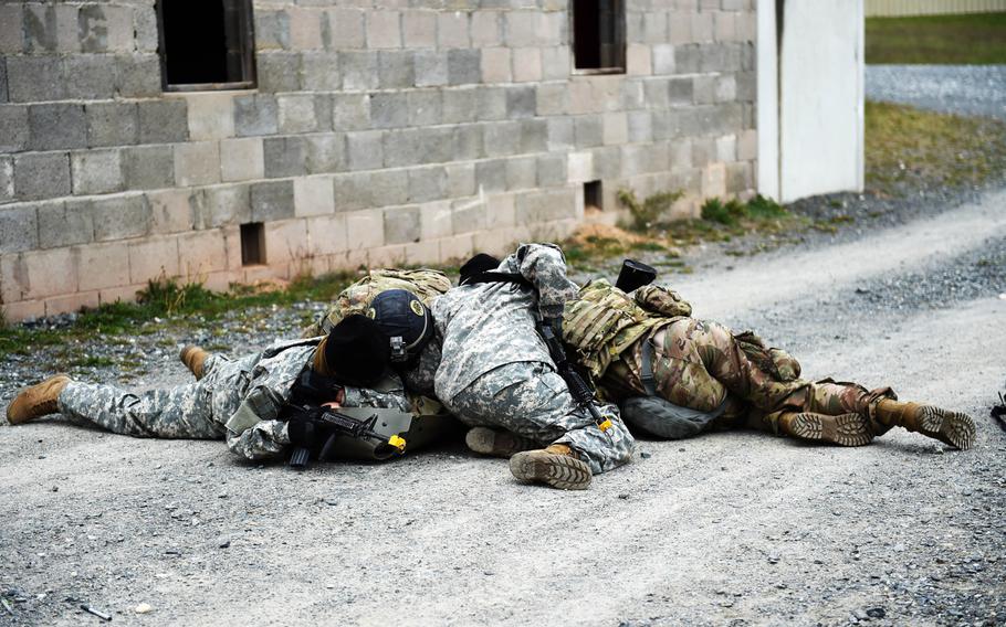 Soldiers competing in the U.S. Army Europe Best Warrior Competition dive on top of a simulated casualty after a mock grenade was thrown to give protection at Grafenwoehr, Germany, Wednesday, May 8, 2019.