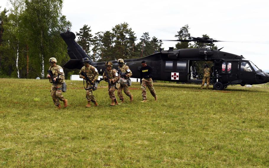 Soldiers competing in the U.S. Army Europe Best Warrior Competition run from a helicopter to the urban combat training area at Grafenwoehr, Germany, Wednesday, May 8, 2019.
