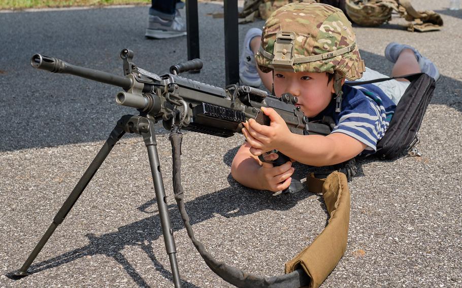 A child poses with an M249 machine gun during the Eighth Army's 75th anniversary celebration at Camp Humphreys, South Korea, Saturday, June 8, 2019.