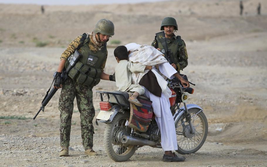 An Afghan soldier helps a child off a motorcycle while conducting searches at a vehicle checkpoint in Shekasteh Tappeh, Helmand province, Afghanistan, July 2014. Afghanistan surpassed Syria as the world's least peaceful country, according to a report from an Australia-based think tank.