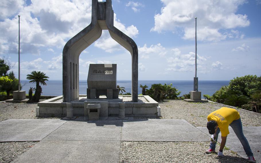 Seaman Jesse Lopez picks up debris at Okinawa Peace Memorial Park in Itoman, Okinawa, Saturday, June 15, 2019.
