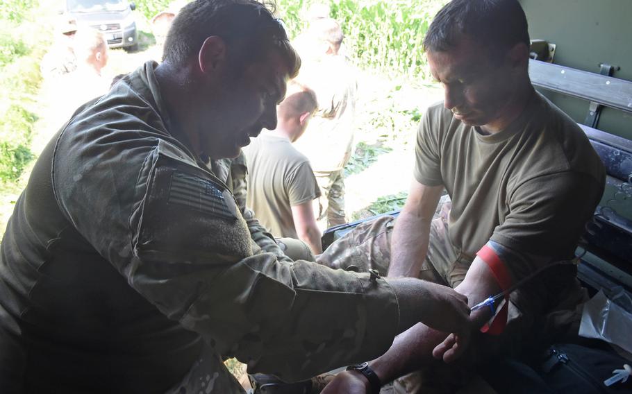 Spc. Per Werner, a medic with the Texas Army National Guard, left, hooks up an IV to Maj. Lee Kain, the operations officer for his unit, during Exercise Swift Response, Friday, June 14, 2019.