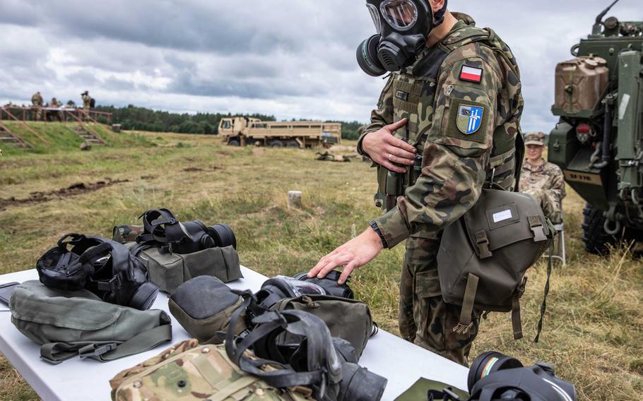 A Polish soldier identifies gear from various NATO allies while wearing a gas mask during the Interoperability Games in Bemowo Piskie, Poland, Saturday, August 3, 2019.