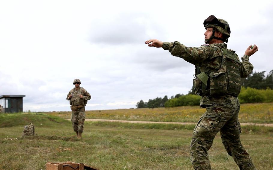 A Croatian soldier throws a grenade while U.S. soldiers judge him during the Interoperability Games in Bemowo Piskie, Poland, Saturday, August 3, 2019.