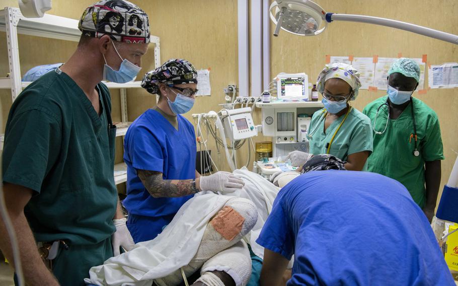 Maj. Paul Hoffmann, an anesthesiologist, and Capt. Julia Ueltzen, a perioperative nurse, both assigned to 44th Medical Brigade from Fort Bragg, N.C., and U.S. Army Capt. Richard Culley, a nurse anesthetist from Fort Belvoir, Va., assist Rwandan medical professionals in preparing a burn victim for a bandage change during a U.S. Army Africa MEDREX in Kigali, Rwanda.