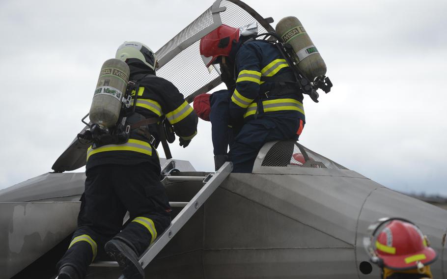 A firefighting team pulls out the pilot — a dummy — from a fighter jet mockup, after putting out a fire on the jet. Firefighters from four NATO nations practiced putting out fires at the USAFE Fire Academy on Ramstein Air Base, Germany, March 11, 2020.