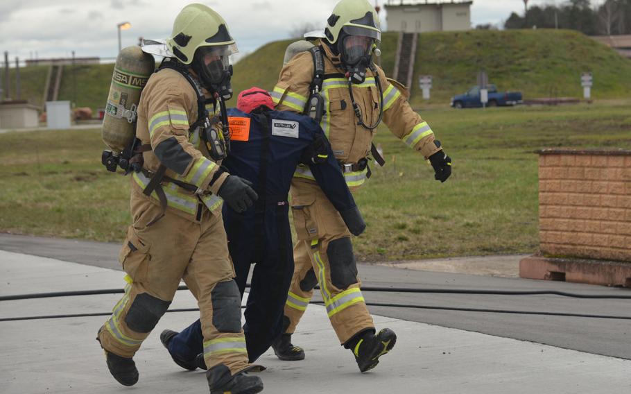 Two members of the Latvian firefighting team carry the pilot, a dummy, away from the mockup of a jet fighter at Ramstein Air Base, Germany, March 11, 2020. Firefighters from four NATO nations practiced putting out fires during training led by the 435th Construction and Training Squadron at the base.