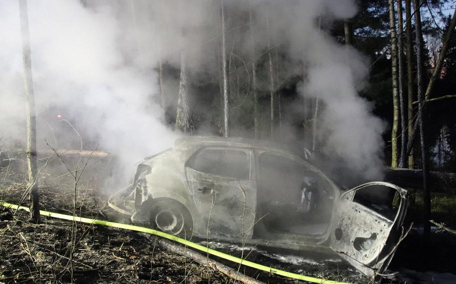 A car smolders near the U.S. Army's training area in Grafenwoehr, Germany, on March 15, 2020. German police are looking for the driver, who fled the scene after crashing the car.