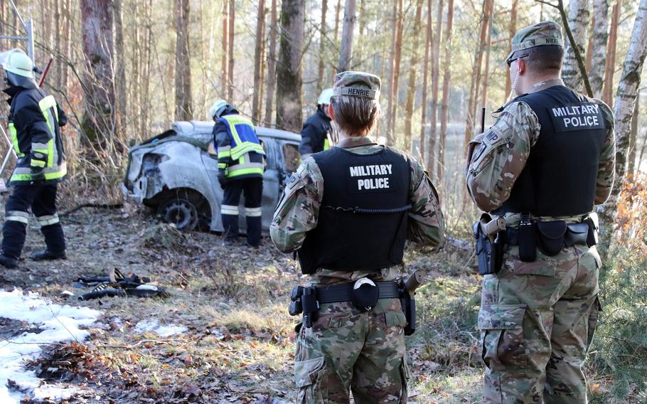 U.S. military police watch as German firefighters investigate the site of a car crash near the U.S. Army training area at Grafenwoehr, Germany, March 15, 2020.