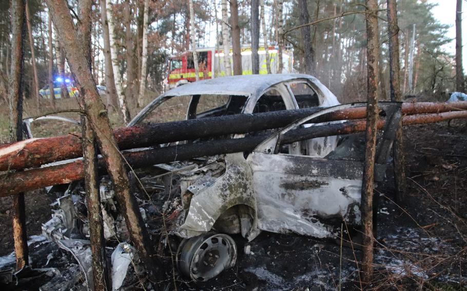 A burned-out car is caught under trees it struck near the U.S. Army's training area in Grafenwoehr, Germany, on March 15, 2020. German police are looking for the driver, who fled the scene after crashing the car.