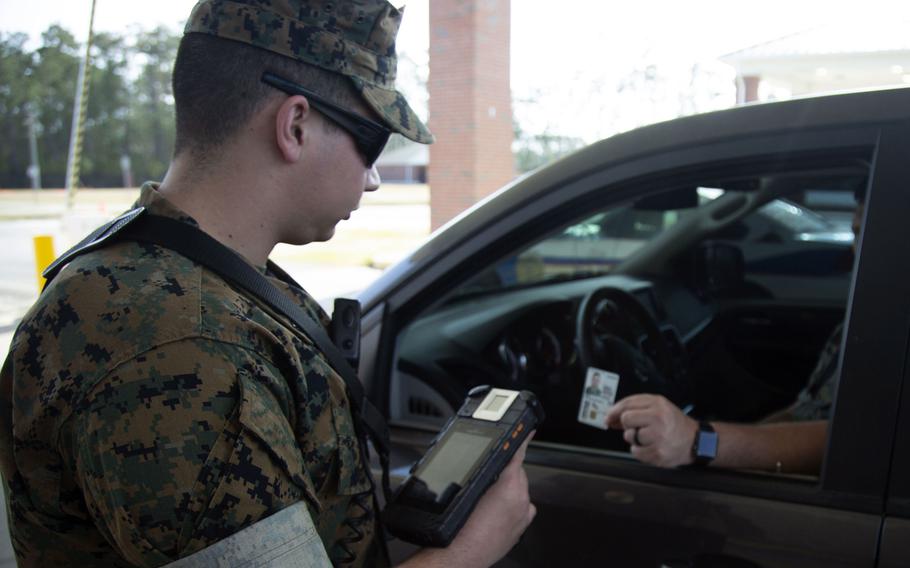 A Marine demonstrates how sentries at Camp Lejeune and Marine Corps Air Station New River, N.C., entry control points limit contact with ID cards. The Marine Corps and Navy are limiting common access card renewals during the coronavirus pandemic, while the Defense Department seeks a technology solution for online security certificates.