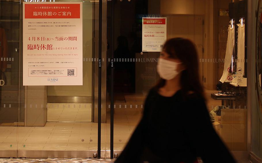A woman strolls past a Tokyo department store that's been closed because of the coronavirus, April 9, 2020.