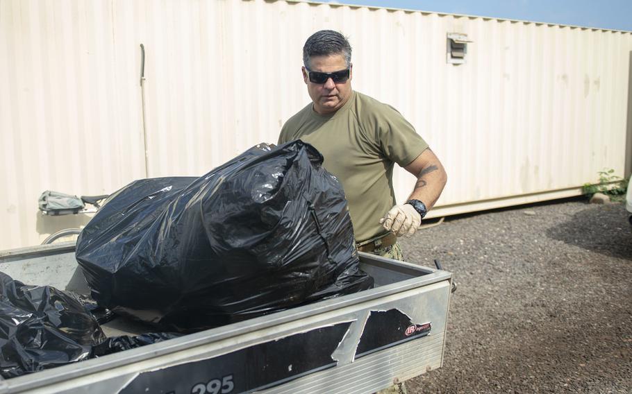 Chief Petty Officer Nicholas Niglio dumps trash, as part of one of many additional cleaning teams tasked as a countermeasure to contain the spread of the coronavirus at Camp Lemonnier, Djibouti, April 6, 2020.