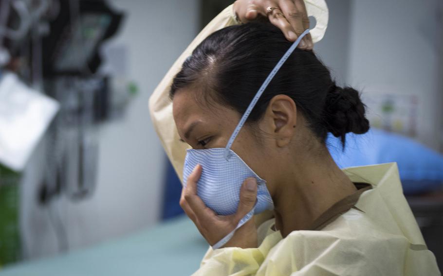 Navy Lt. Gail Evangelista, a nurse assigned to Naval Hospital Rota, Spain, dons a facemask prior to interacting with a patient at the Michaud Expeditionary Medical Facility at Camp Lemonnier, Djibouti, April 16, 2020.