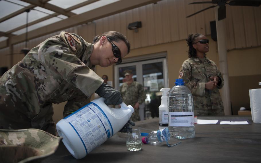 Air Force Maj. Leah Chapman, left, Combined Joint Task Force-Horn of Africa Surgeon Cell public health officer, demonstrates creating a cleaning solution using bleach and water during a training session for the high-traffic area disinfectant team at Camp Lemonnier, Djibouti, March 27, 2020.