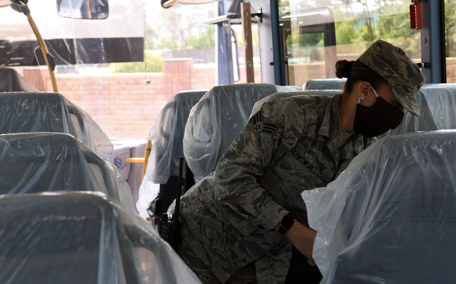 Senior Airman Andrea Bonkowski, a vehicle operator with the 86th Vehicle Readiness Squadron at Ramstein Air Base, Germany, looks over cloth bus seats with disposable plastic coverings, May 12, 2020. The squadron is using the coverings to reduce the risk of coronavirus spreading among passengers.
