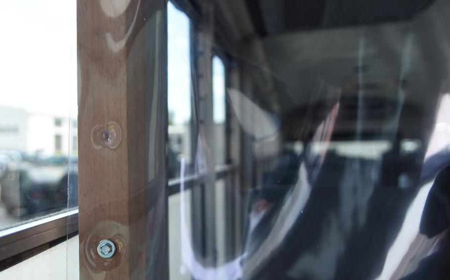 A plastic sheet is nailed to a piece of wood to create a clear barrier between passengers and the driver inside a government bus at Ramstein Air Base, Germany.