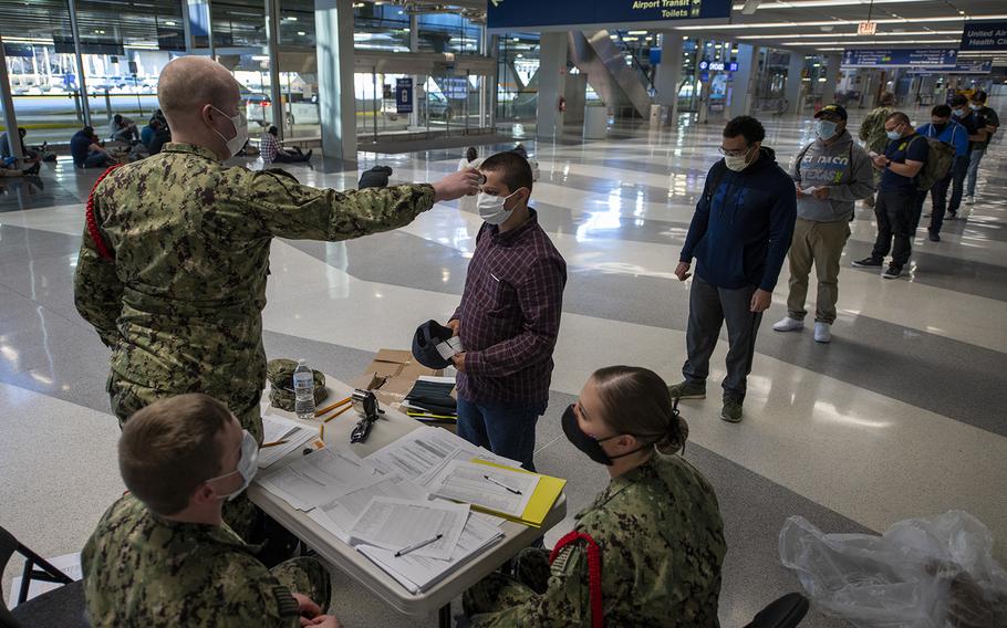 Staff assigned to Recruit Training Command process recruits as part of a preliminary health screening at Chicago O'Hare Airport in Chicago, Ill., April 21, 2020.