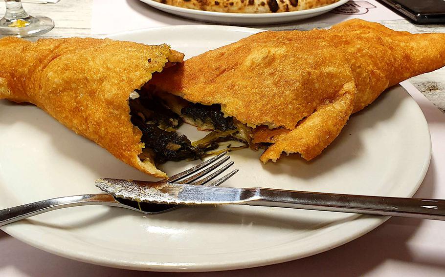 A cut-open fried calzone shows its contents of broccoli rabe, sausage, and mozzarella cheese, at DoDo's Verace Pizza Napoletana in Sacile, Italy. The restaurant, which was open only for take-out or home delivery at the height of the coronavirus in Italy, serves pizza, calzones, and other traditional foods from Naples.
