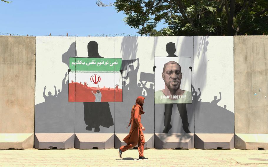 A person walks past a mural near the fortified Green Zone in Kabul on Monday, June 15, 2020, dedicated to George Floyd and three Afghan migrants who died in Iran.