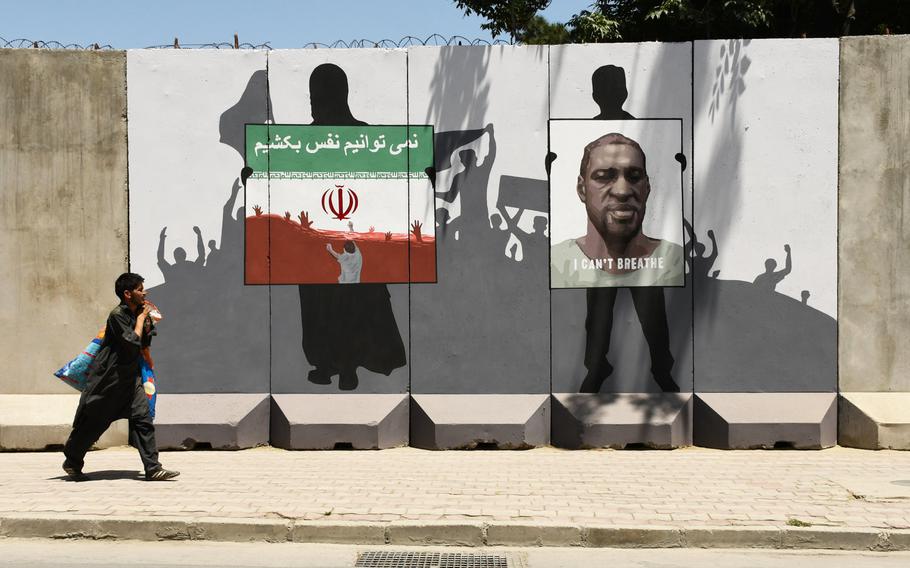 A man walks past a mural near the fortified Green Zone in Kabul on Monday, June 15, 2020, dedicated to George Floyd and three Afghan migrants who died in Iran. 