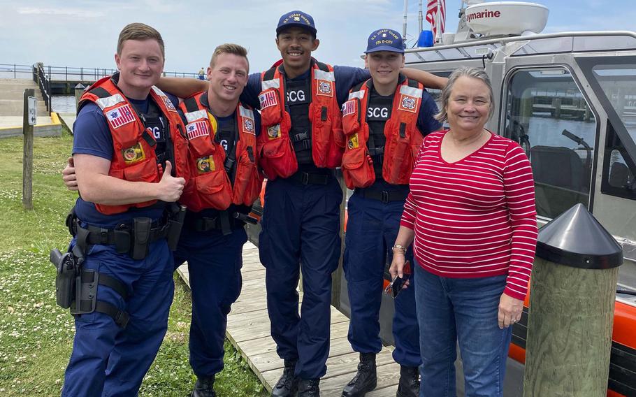 A Coast Guard boat crew from Station Elizabeth City pose with a survivor rescued from a sinking houseboat on the Scuppernong River in Albemarle Sound, N.C., June 13, 2020. From left are Petty Officer 2nd Class Aaron Reese, Fireman Christopher McCann, Seaman Michael Bland, Petty Officer 3rd Class Victoria Cloin and one of the survivors.