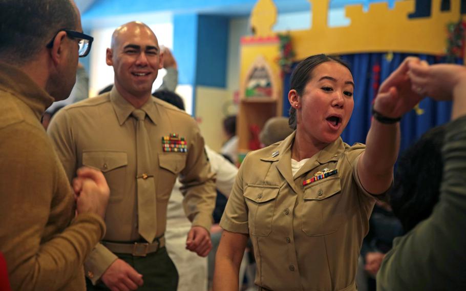 A Marine and a sailor dance with students during a Christmas party at a school in Acireale, Italy, Dec. 11, 2018. An Italian decree states that people are not allowed to dance in public through Sept. 7, 2020 due to coronavirus concerns. U.S. bases in the country are complying with the rule.