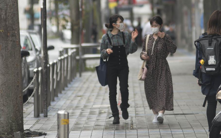 People wear masks to guard against the coronavirus while strolling in Yokosuka, Japan, Sept. 23, 2020.