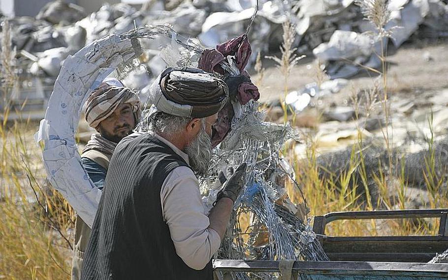 Two workers untangle barbed concertina wire on Saturday, Oct. 31, 2020, in Kandahar, Afghanistan, at a bazaar where goods that once belonged to U.S. and NATO troops and contractors at Kandahar Airfield are sold to locals.