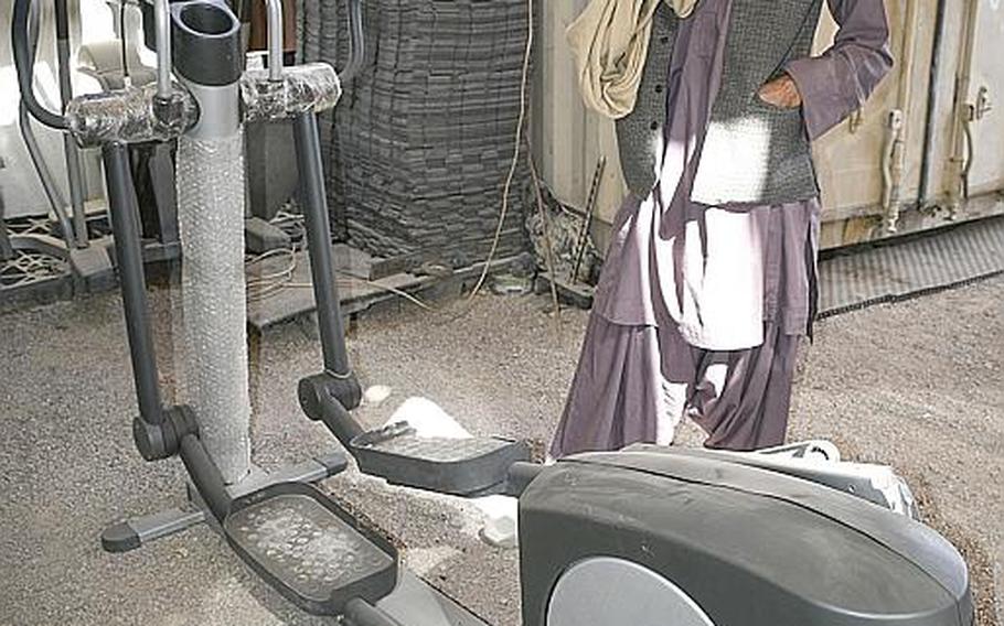 Amanullah, a vendor at a shop in Kandahar, Afghanistan, displays Saturday, Oct. 31, 2020, a new exercise machine — still in its plastic packaging — that he obtained from contractors working at Kandahar Airfield. Hundreds of containers filled with generators, refrigerators and other valuable goods have been leaving the base as part of the ongoing drawdown of U.S. troops, Amanullah and other vendors said.