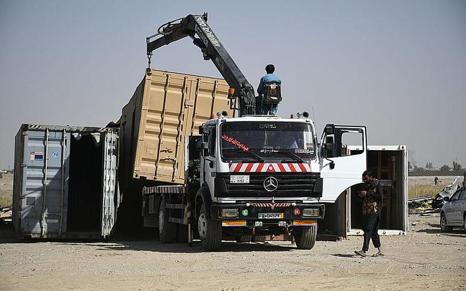 Locals in Kandahar, Afghanistan, unload a shipping container Saturday, Oct. 31, 2020, at a bazaar where vendors sell items thrown out by troops and contractors at Kandahar Airfield. More than 1,000 workers at the site pick through each container to find treasures among the trash to sell.