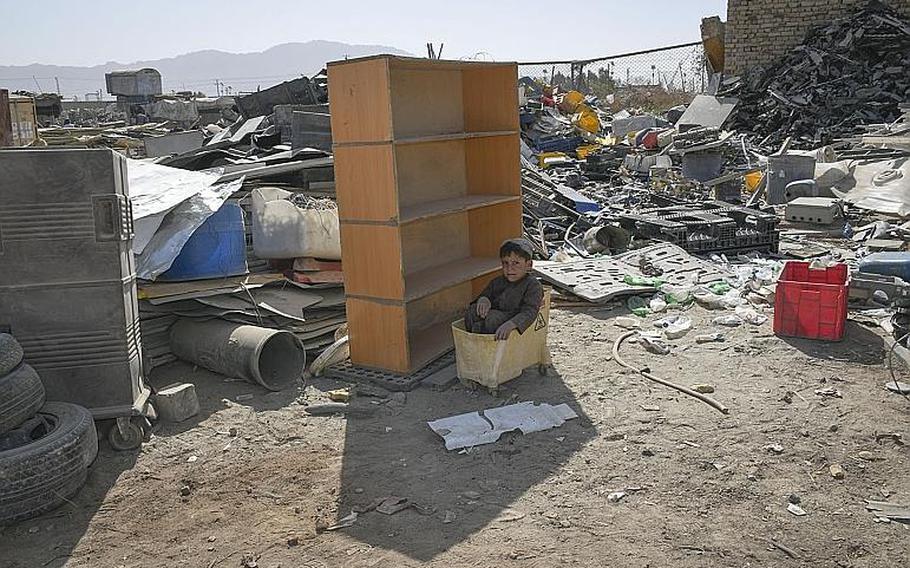 A child sits in a mop bucket hidden in the shade of shelving on Saturday, Oct. 31, 2020, at the ''Bush Bazaar'' in Kandahar, Afghanistan, where items thrown out by U.S. and NATO troops and contractors are available for purchase.