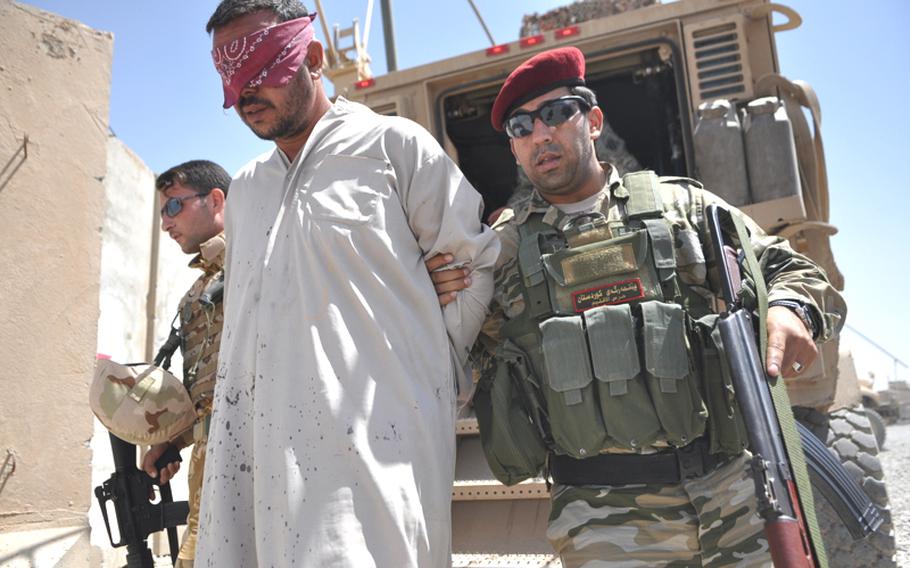 Soldiers with the Iraqi army and Kurdish peshmerga lead a suspected insurgent from an American armored truck in northern Ninevah province. The U.S. military announced that combat operations will end by Aug. 31, but American forces can act on intelligence to go after insurgents as they did in this case, partnering with Iraqi security forces, to capture the man.